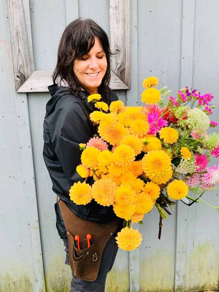 a woman holding a large bouquet of bright flowers